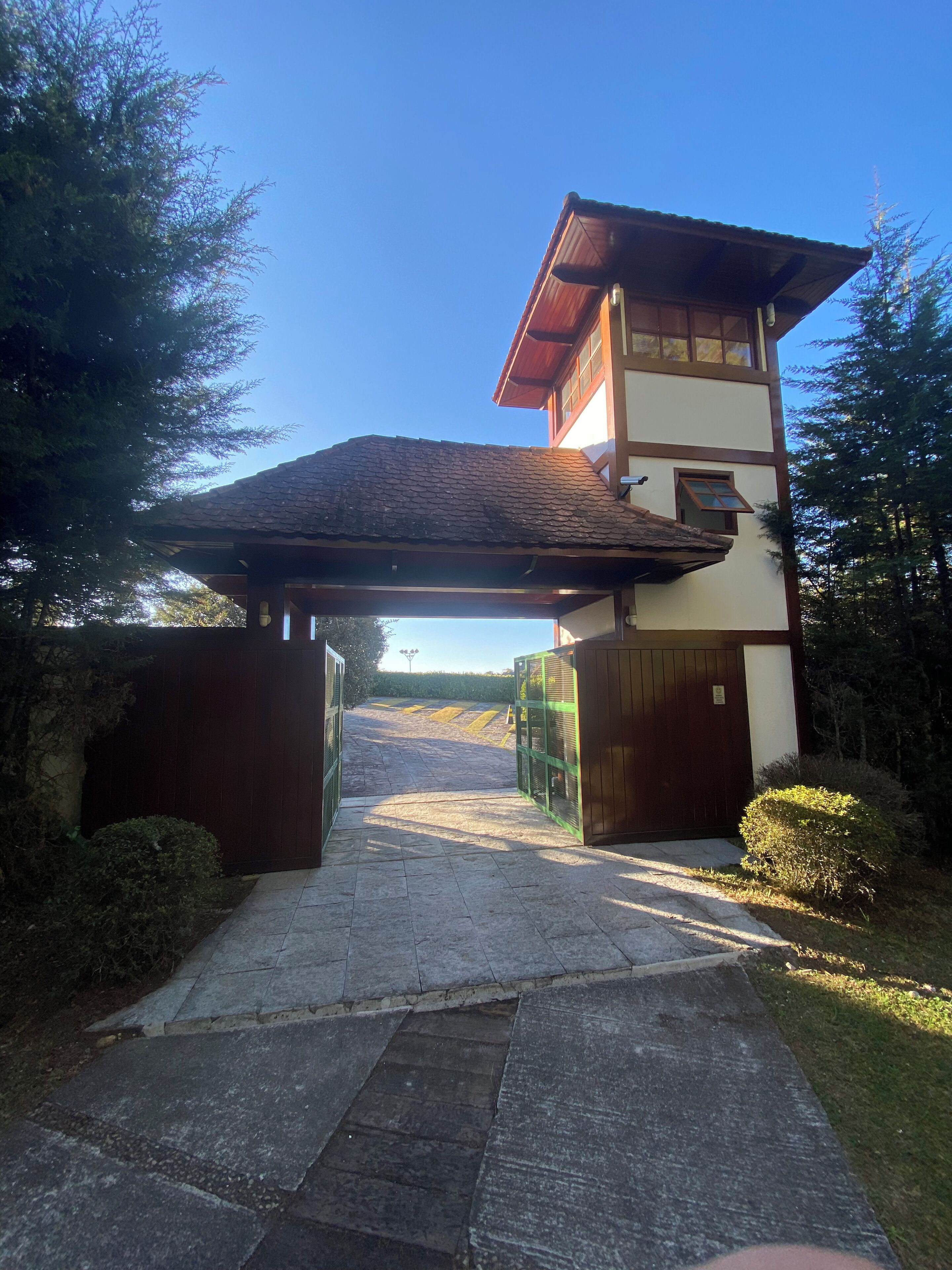 A traditional building with a sloped roof, a wooden gate, and a paved pathway leading to a gate.