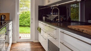 A modern kitchen with white cabinets, stainless steel appliances, and a large window.