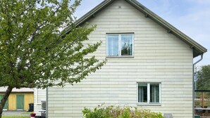 Een twee verdiepingen tellend huis met een puntige dakkapel en een voortuin.