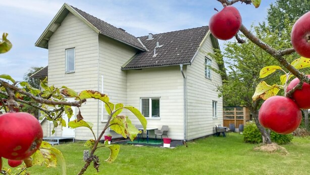 Een huis met twee verdiepingen, een schuin dak, een voortuin en een verzorgd gazon.