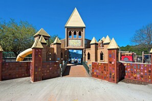 A castle-themed play area with a slide, hand-painted walls, and a sign reading "Perdido Kid's Park".