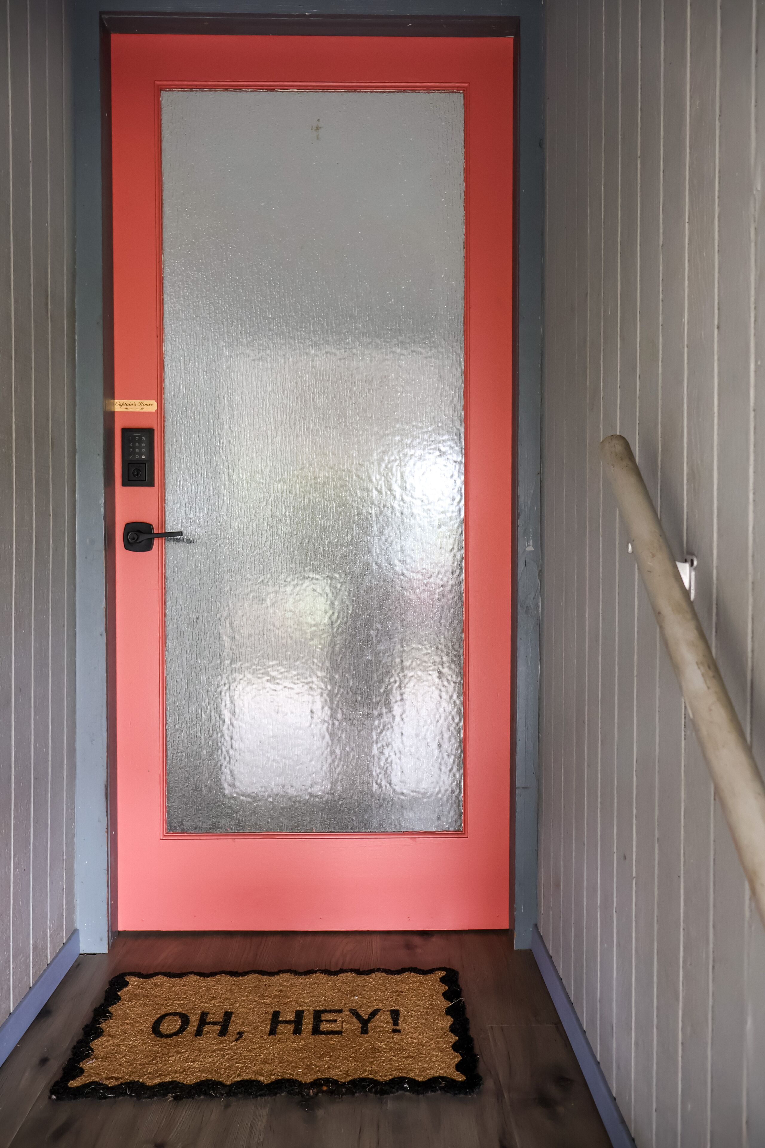 A red-framed door with a glass panel and a keypad lock.