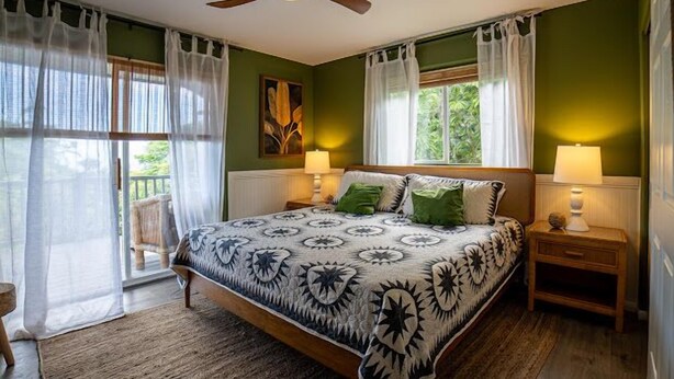 A bedroom with a bed, two bedside tables, a ceiling fan, and a window with curtains.
