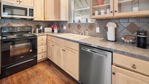 A kitchen with wooden cabinets, a stainless steel dishwasher, a microwave, an oven, and a coffee bar. - *Mins To Methodist Hospital* Lux & Cozy* (San Antonio)