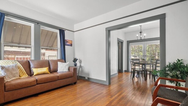 A spacious living room with a brown leather sofa, wooden flooring, and a dining area with a table and chairs. - *Mins To Methodist Hospital* Lux & Cozy* (San Antonio)