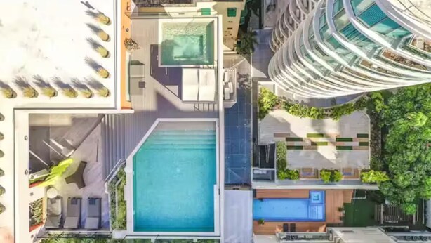 A modern building with a rooftop pool, a covered outdoor area, and a curved glass facade. - NewExclusive Apartment Downtown, GYM, POOL&MORE 407 (Santo Domingo)