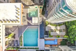 A modern building with a rooftop pool, a covered outdoor area, and a curved glass facade. - New, exclusive apartment in the city center, gym, pool, and more 407 (Santo Domingo)