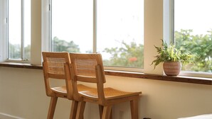 A room with a wooden dining table, two wooden chairs, a potted plant, and a beige sofa. - Lihau Boho House (Kailua-Kona)