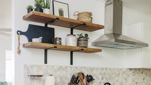 A kitchen with white cabinets, a wooden countertop, a stainless steel range hood, and a tiled backsplash. - Lihau Boho House (Kailua-Kona)