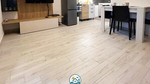 A modern kitchen with a built-in TV, a refrigerator, and a dining area with a table and chairs. - ⭐️ Luminis Holiday Home - Comfort and the sea at your fingertips ⭐️ (Porto Torres)
