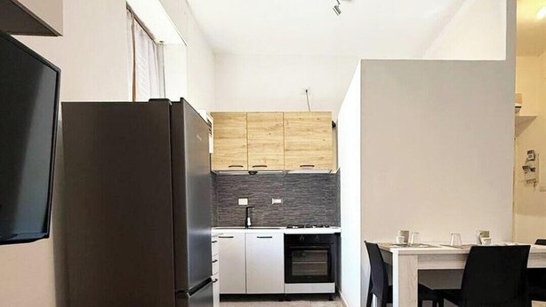 A modern kitchen with a built-in oven, a refrigerator, and wooden cabinets. - ⭐️ Luminis Holiday Home - Comfort and the sea at your fingertips ⭐️ (Porto Torres)