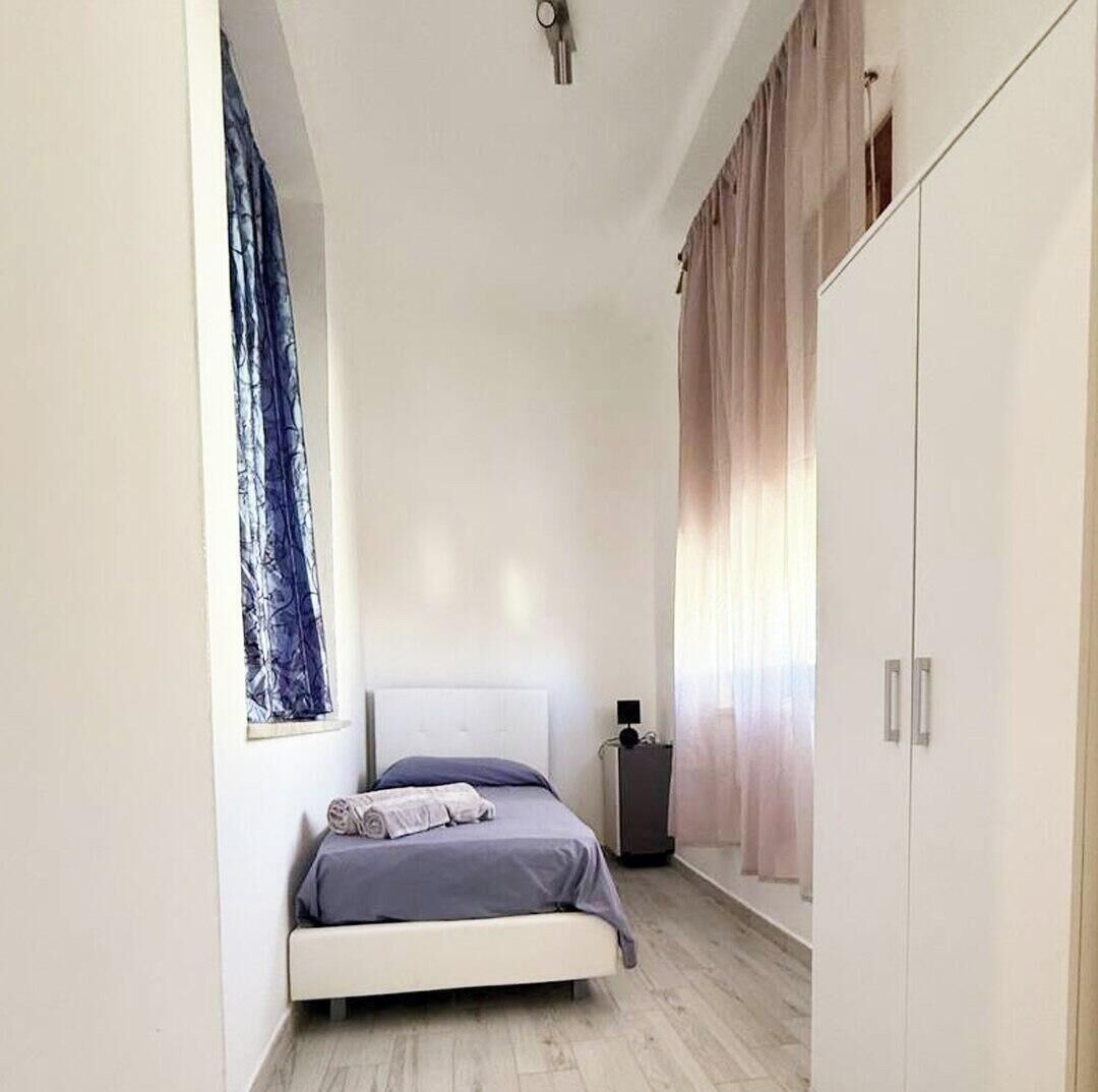 Un dormitori amb un llit, un armari i una finestra amb cortines.