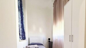 A bedroom with a bed, a wardrobe, and a window with curtains. - ⭐️ Luminis Holiday Home - Comfort and the sea at your fingertips ⭐️ (Porto Torres)
