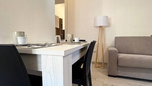 A dining area with a wooden table set for two, black chairs, a floor lamp, and a sofa in the background. - ⭐️ Luminis Holiday Home - Comfort and the sea at your fingertips ⭐  ️ (Porto Torres)