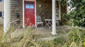 Ein Haus mit roter Tür, Hausnummer 418, und einer Veranda mit weißen Stühlen und einem Tisch.