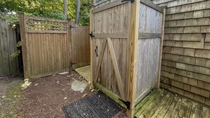 Ein Holzschuppen mit einer Metalttür, einem Holzzaun und einer Holzterrasse.