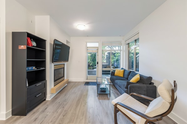 Ein modernes Wohnzimmer mit einer Couch, einem Couchtisch, einem Fernseher und einem Kamin.