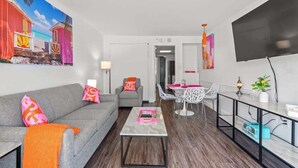 A modern living room with a sofa, coffee table, and a dining area with chairs and a table.