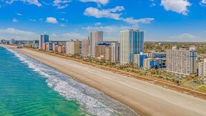 A coastal cityscape with a beach, high-rise buildings, and a clear sky.