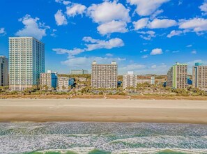 Un paisaje urbano costero con rascacielos, una playa y olas del océano.