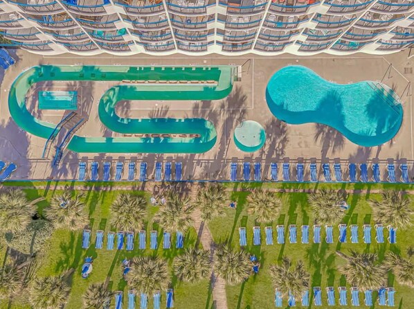 Un resort con piscina, varias zonas de baño y filas de cabañas frente a la playa.