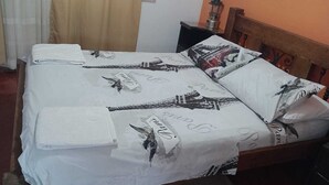 Ein Bett mit weißer Bettdecke, verziert mit einem Vogelmotiv und dem Wort 'Paradise'.