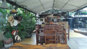 Ein Restaurant mit Holztischen und -stühlen, einer Huthalterung und Blick ins Freie.