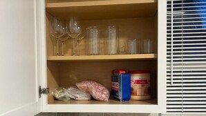 Une cuisine équipée d’un meuble intégré contenant des verres à vin, une machine à café et un grille-pain.