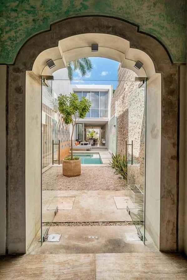 An interior courtyard with a pool, a potted plant, and a view of a building through an arched doorway.