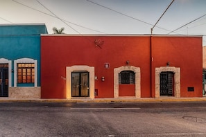 A street view with a red building featuring two doors and a small window, adjacent to a blue building with a window and a door.