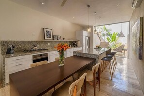 Een moderne keuken met een centraal eiland, barstoelen en een eettafel.