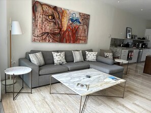 A modern living room with a grey sofa, a marble coffee table, and a large abstract painting on the wall.