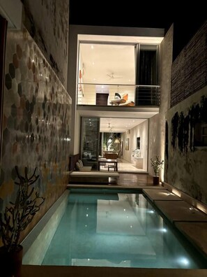 A modern house with a swimming pool, a dining area, and a second-floor balcony.