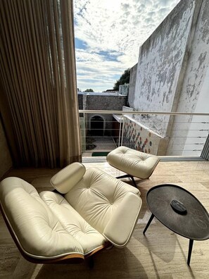 A modern balcony with a cushioned sofa and a small table, overlooking a cityscape.