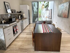A modern kitchen with a central island, built-in appliances, and a large window providing natural light.