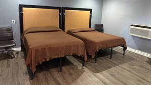 A room with two single beds, a desk, a chair, and an air conditioning unit. - Driftwood Motel - Colton (Colton)