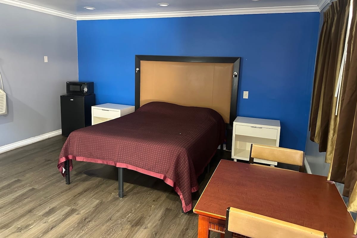 Ein Hotelzimmer mit einem Bett, Nachttischen, einem Schreibtisch und einem Stuhl.