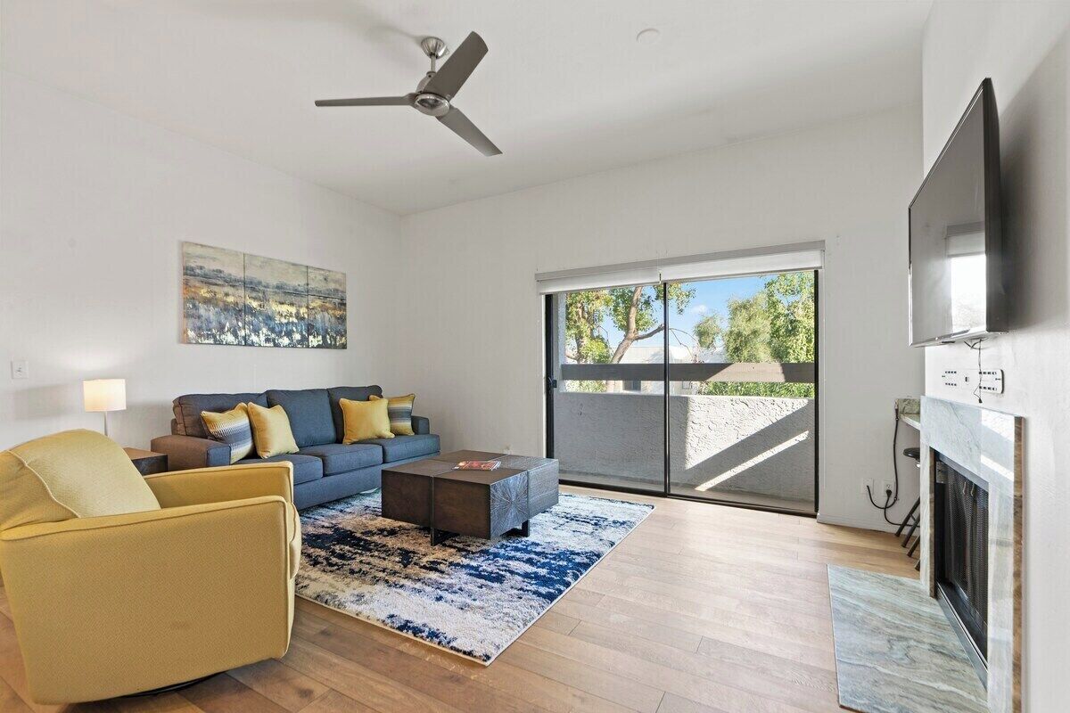 A modern living room with a sofa, armchair, coffee table, and fireplace.