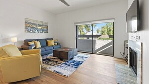 A modern living room with a sofa, armchair, coffee table, and fireplace. - Modern Scottsdale Condo with Private Patio, Community Pool and Hot Tub (Scottsdale)