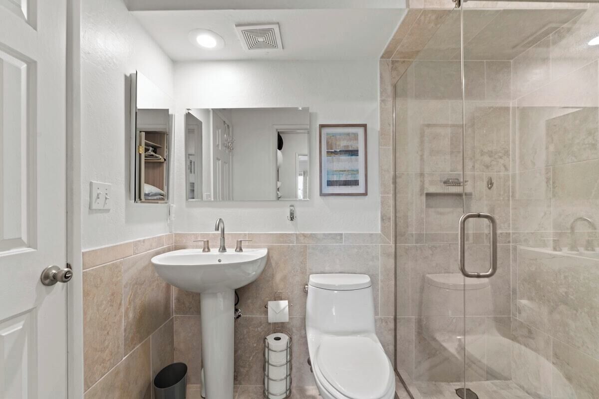A modern bathroom with a sink, toilet, and glass-enclosed shower.