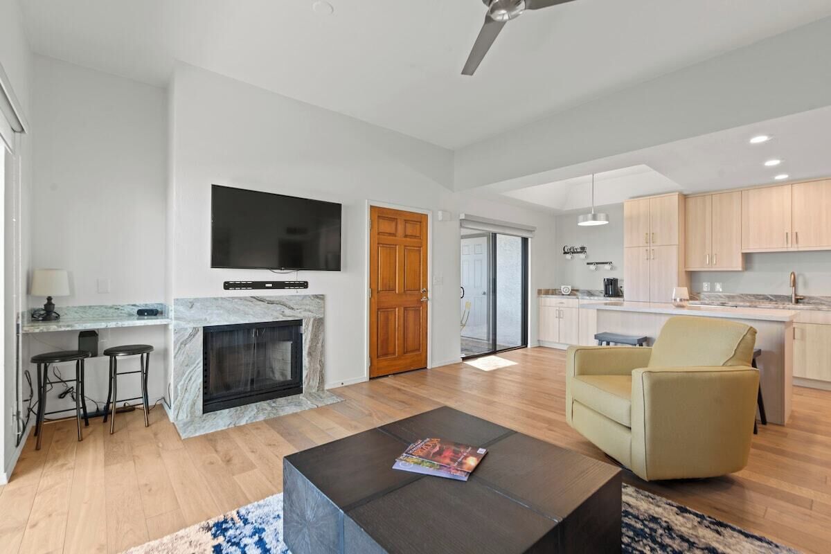 A modern living room with a fireplace, a TV mounted on the wall, and a comfortable seating area.