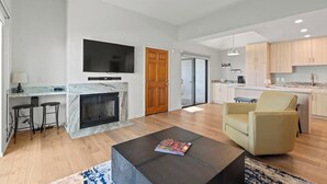 A modern living room with a fireplace, a TV mounted on the wall, and a comfortable seating area. - Modern Scottsdale Condo with Private Patio, Community Pool and Hot Tub (Scottsdale)