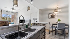 A modern kitchen with a large island, stainless steel sink, and pendant lighting. - Woodland Springs with Community Pool, Hot Tub, Tennis, Sauna & Fitness Center C209 (Scottsdale)