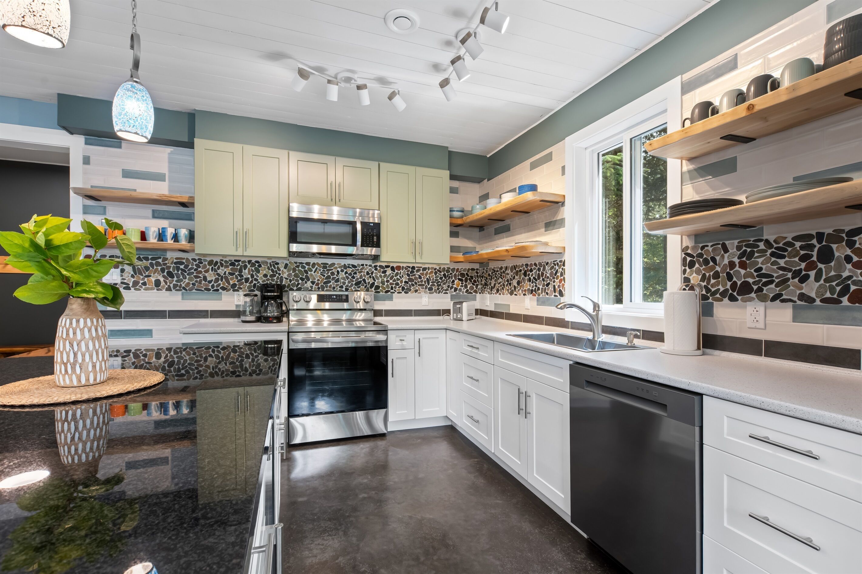 A modern kitchen with white cabinets, a granite countertop, a built-in oven, and a dishwasher.