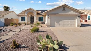 A residential house with a garage, a driveway, and a landscaped garden with cacti. - Red Mountain Retreat - 4B/2B with Private Pool for your Arizona Getaway (Mesa)