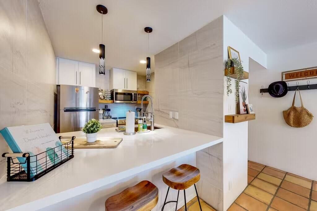 A modern kitchen with white cabinetry, stainless steel appliances, and a central island with stools.