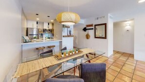 Une cuisine moderne avec des meubles blancs, un réfrigérateur en acier inoxydable et un luminaire suspendu.