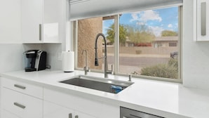 A modern kitchen with a built-in sink, a coffee maker, and a window with a view of the outside.