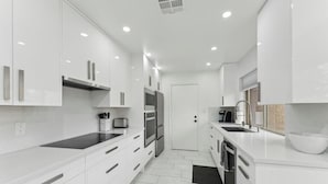 A modern kitchen with white cabinetry, stainless steel appliances, and a black countertop.