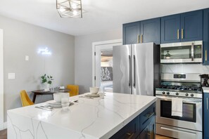 A modern kitchen with a marble island, stainless steel appliances, and blue cabinets. - Eclectic Escape with Private Pool in Scottsdale - Arizona basecamp (Scottsdale)